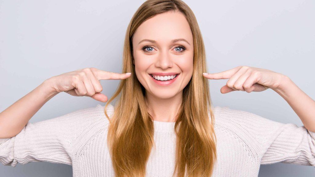 Woman Smiling and Pointing to Her Teeth