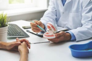 Dentist pointing to teeth model to patient