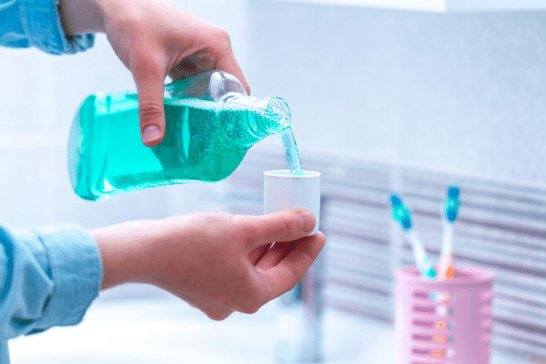 An individual pouring Listerine into a small cup